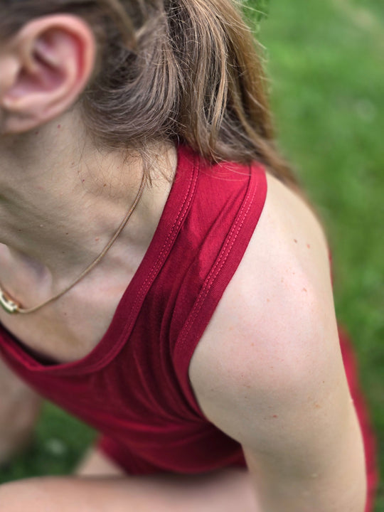Person wearing a red tank top sitting on grass