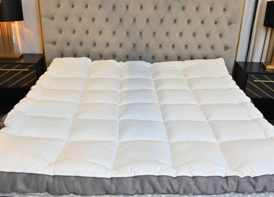 White quilted mattress cover on a bed with a tufted headboard