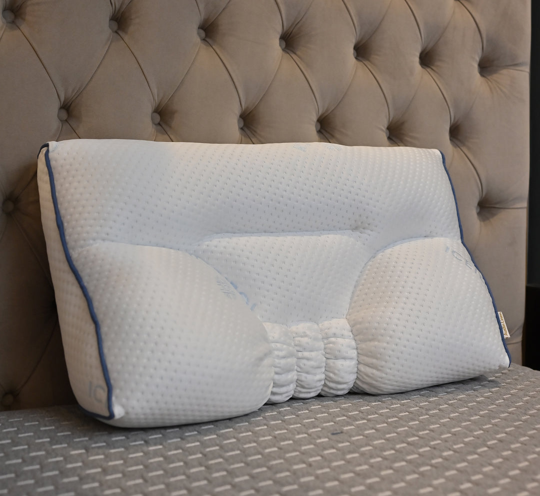 Ergonomic pillow on a bed with a tufted headboard