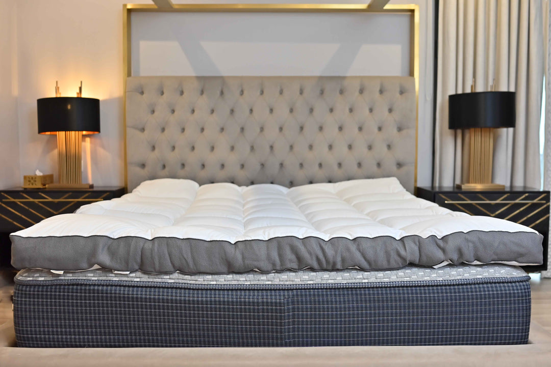Mattress on a bed with a decorative headboard and lamps in a bedroom setting