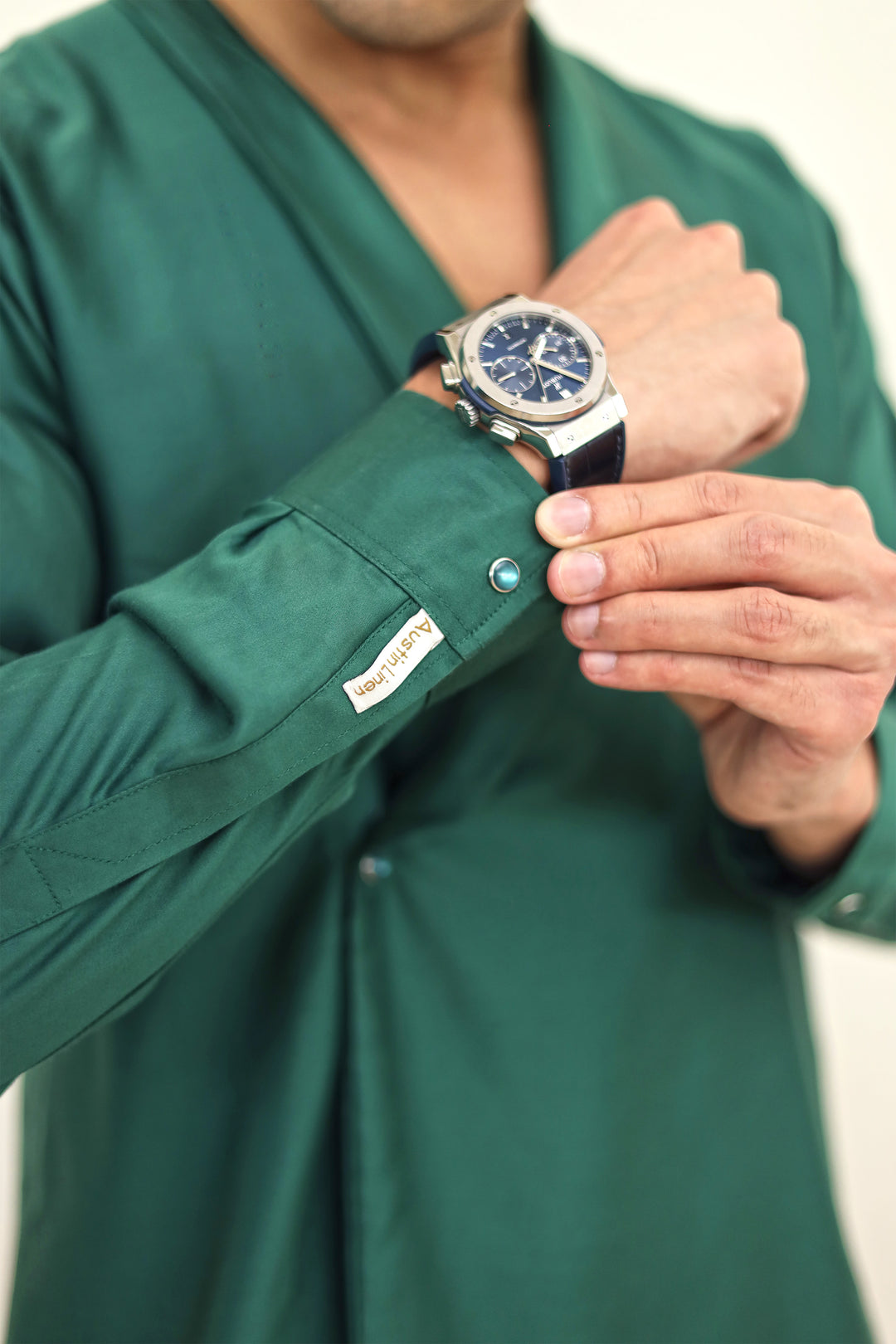 Person wearing a green scrub top with a watch on a blurred background