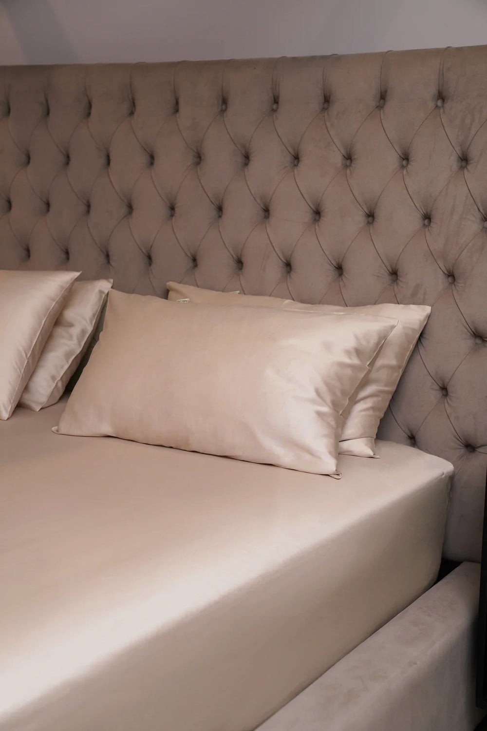 Beige bed with tufted headboard and pillows