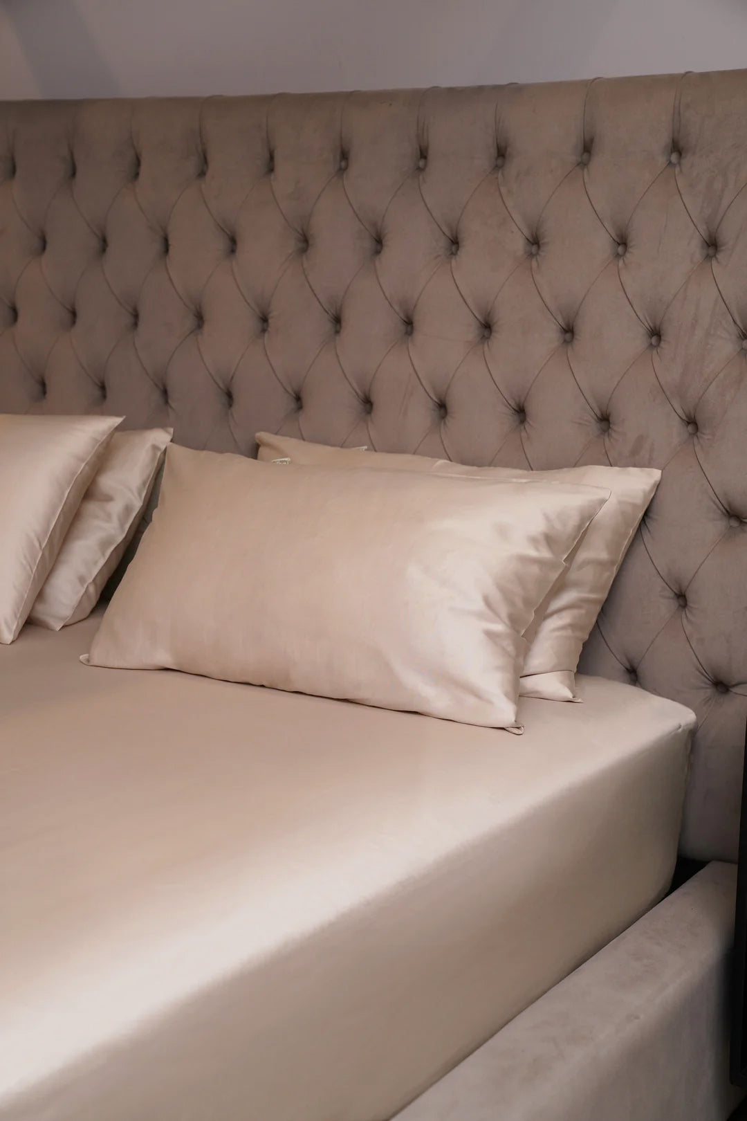 Beige bed with tufted headboard and pillows