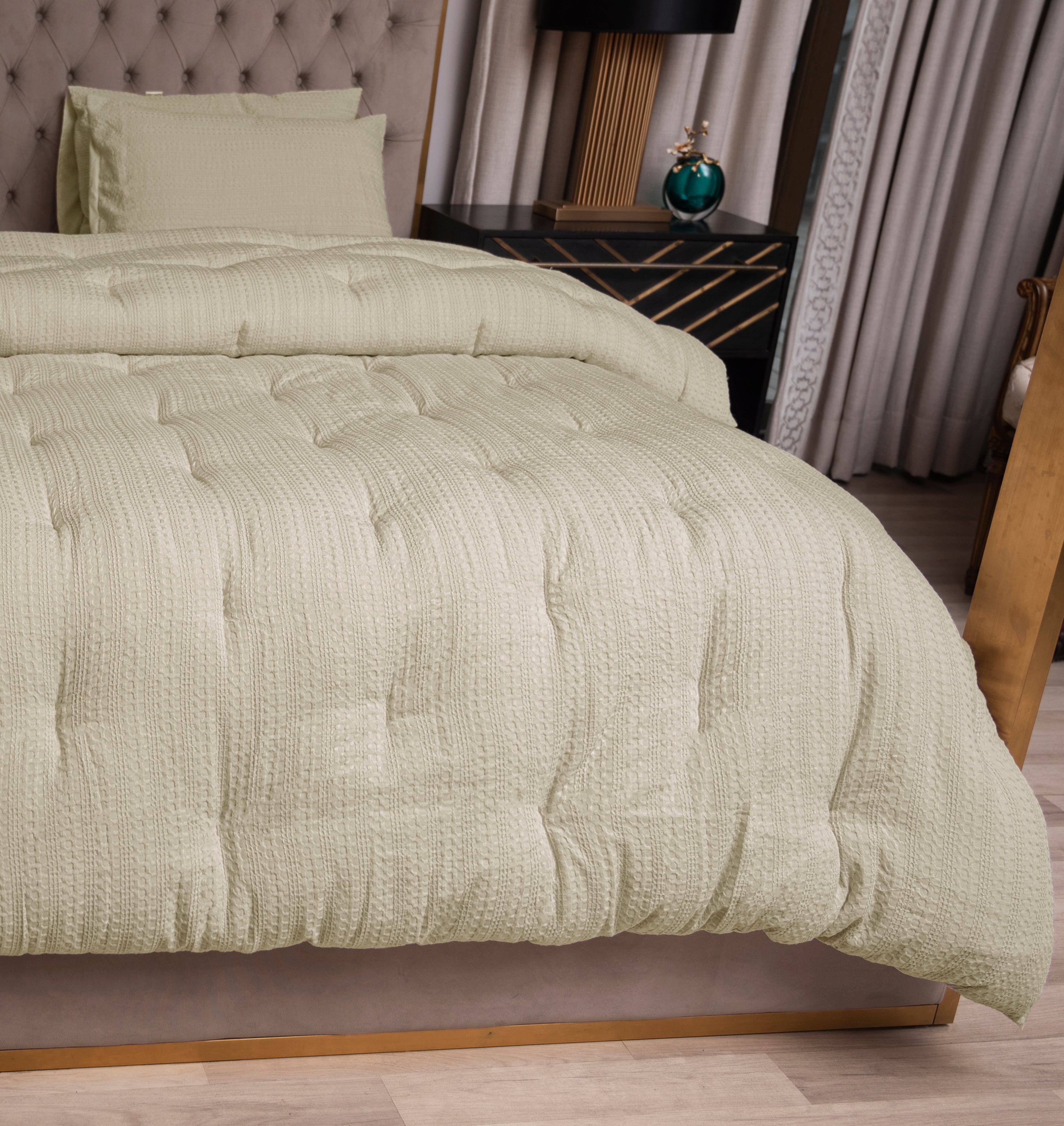 Bed with textured green bedding in a bedroom setting