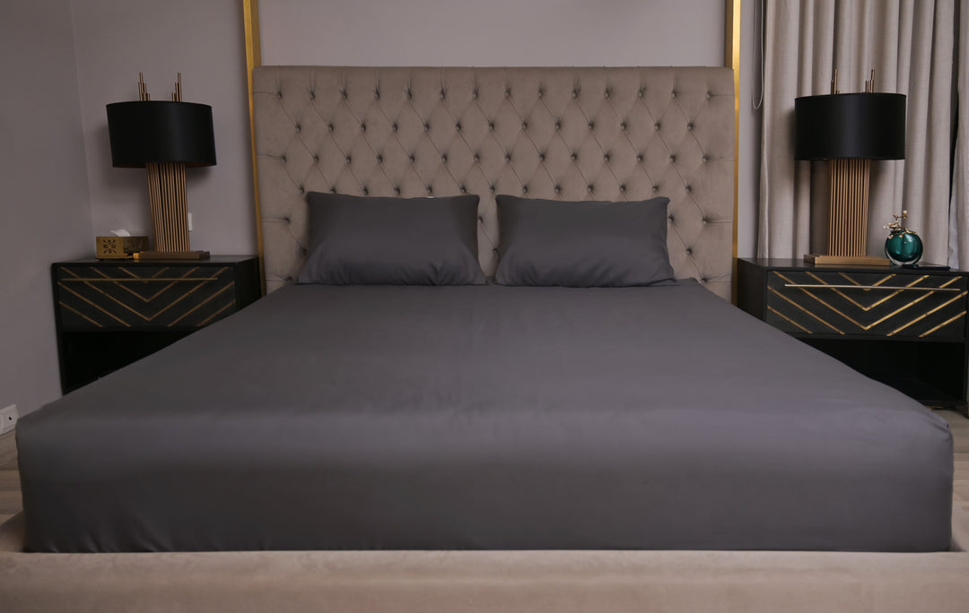 Gray bedspread on a bed with matching pillows in a bedroom setting.