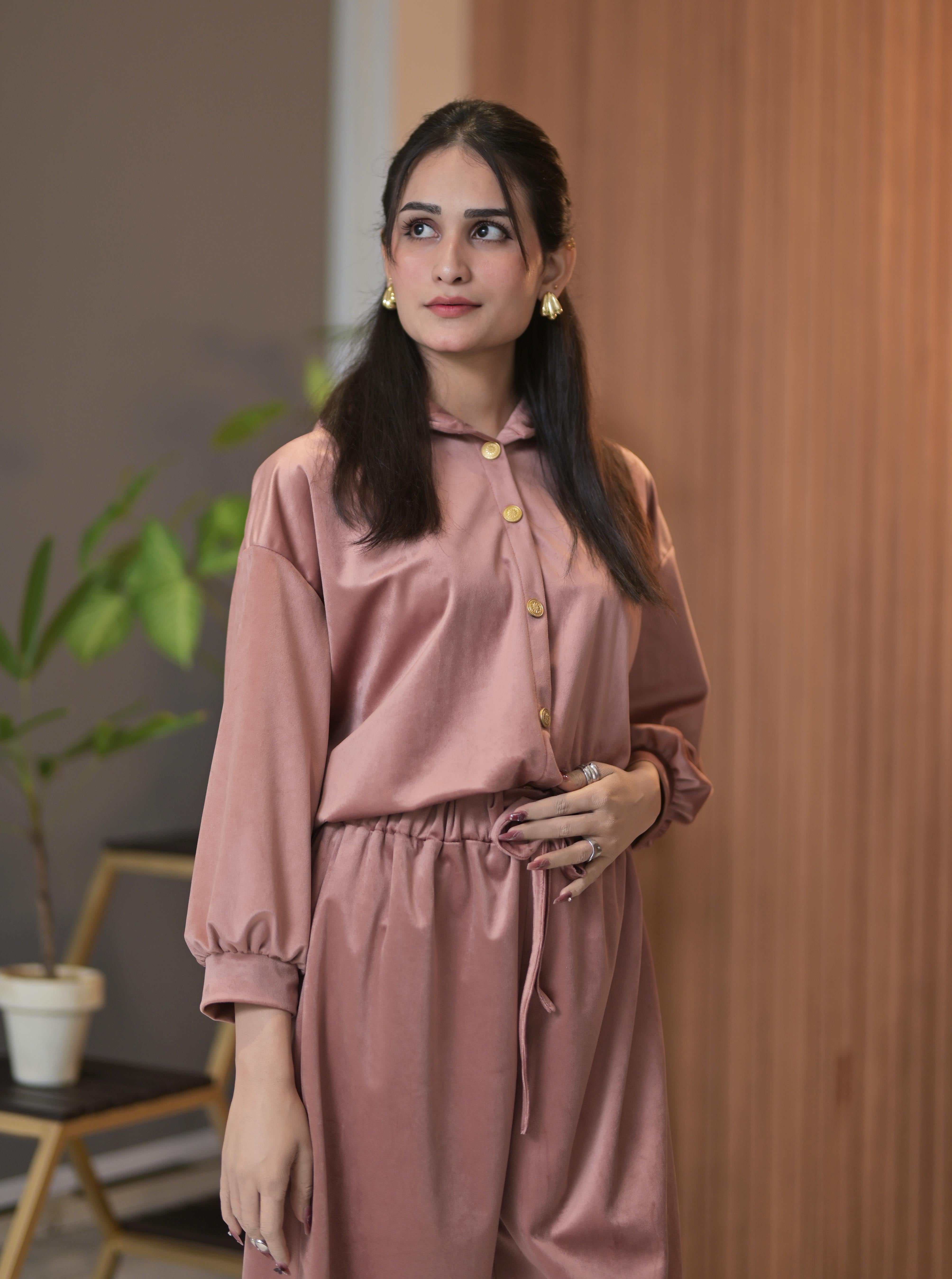 Woman wearing a pink outfit with buttons indoors