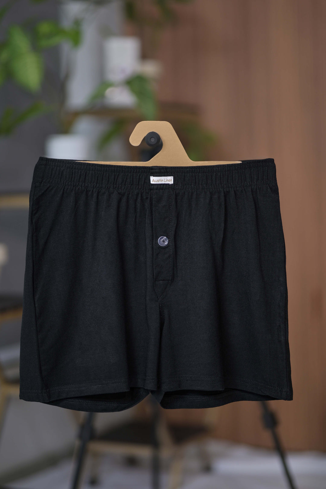 Black boxer shorts on a hanger with a blurred indoor background