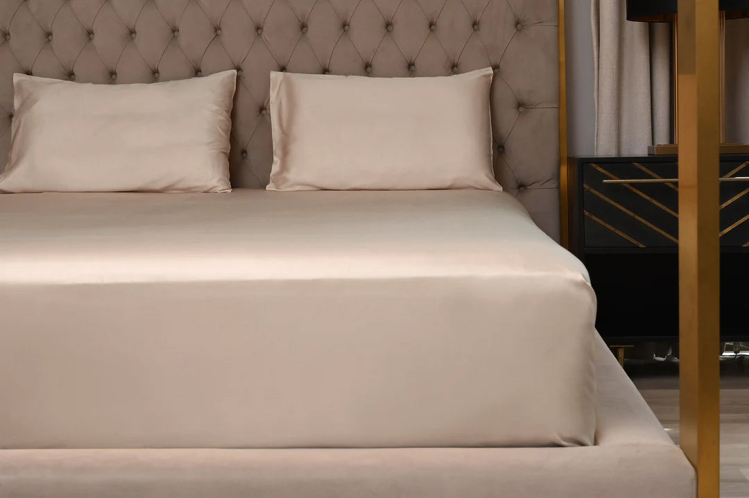 Beige bed with pillows against a tufted headboard in a bedroom setting.