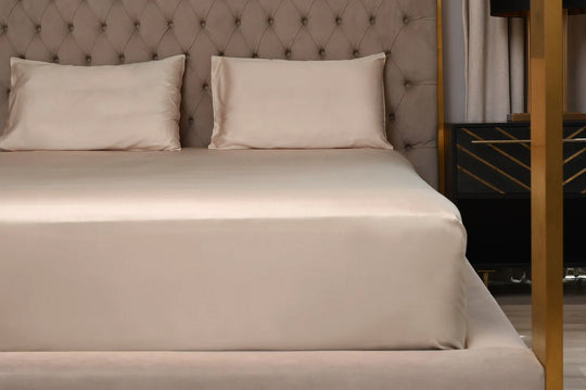 Beige bed with pillows against a tufted headboard in a bedroom setting.