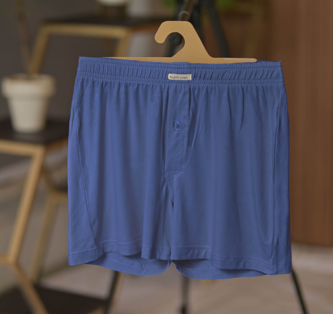 Blue boxer shorts on a hanger with a blurred indoor background