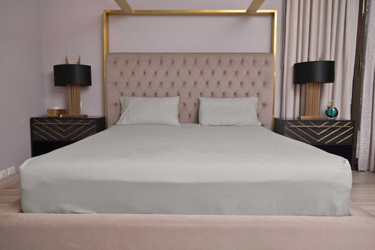 Neatly made bed with gray bedding in a bedroom setting.